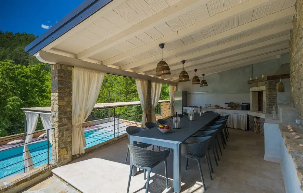 Outdoor dining area beside pool with forest view.