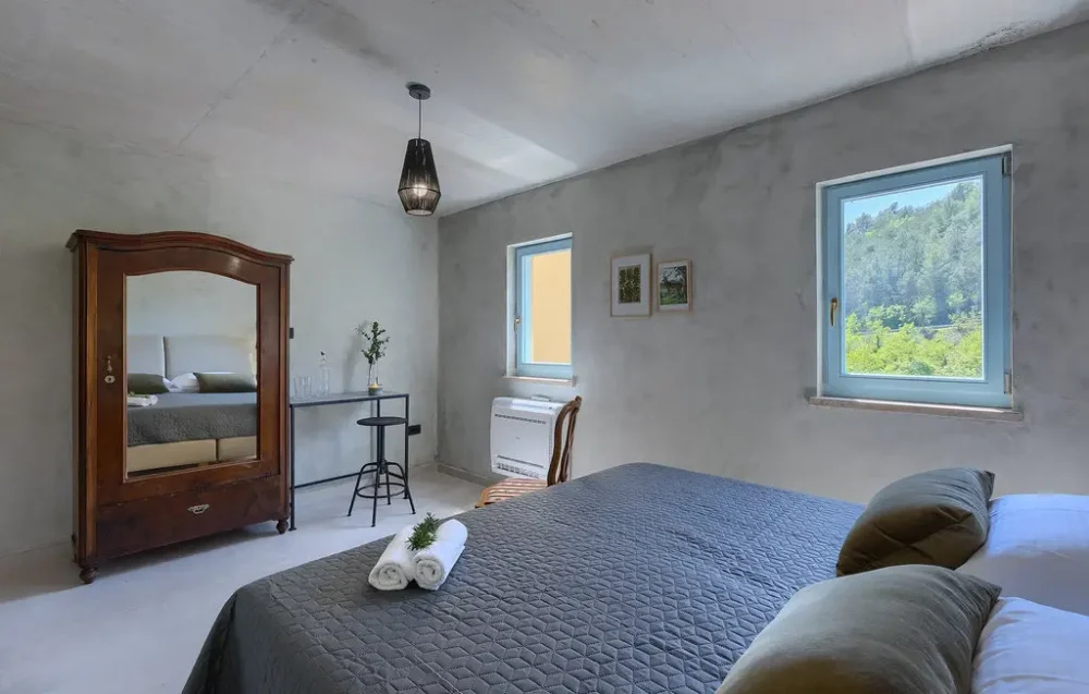Cozy bedroom with mirror and nature view windows.