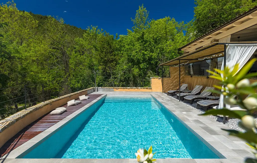 Sunny outdoor pool with lounge chairs and greenery.
