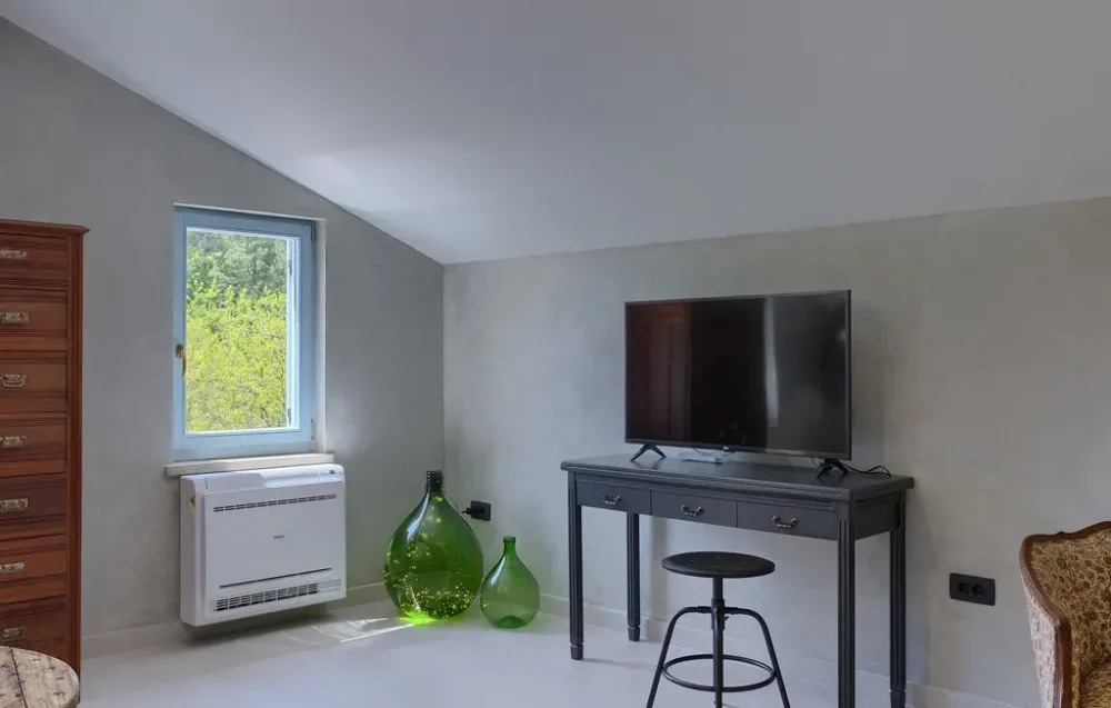 Modern room with TV, window, and green vases.
