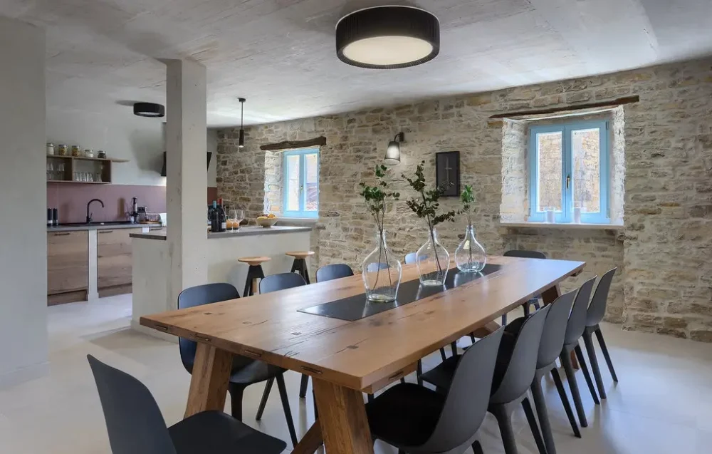 Rustic dining room with stone walls and wood table.