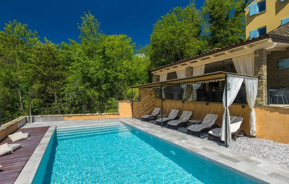 Outdoor pool with lounge chairs and shaded terrace.