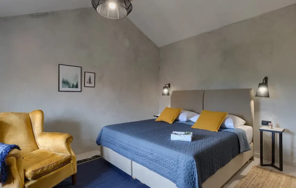Modern bedroom with yellow chair and blue bedding.