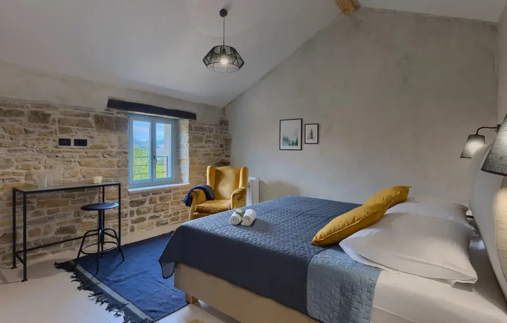 Cozy bedroom with exposed stone wall and window.