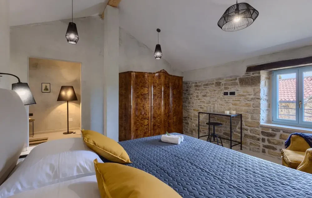 Cozy bedroom with rustic decor and stone walls.