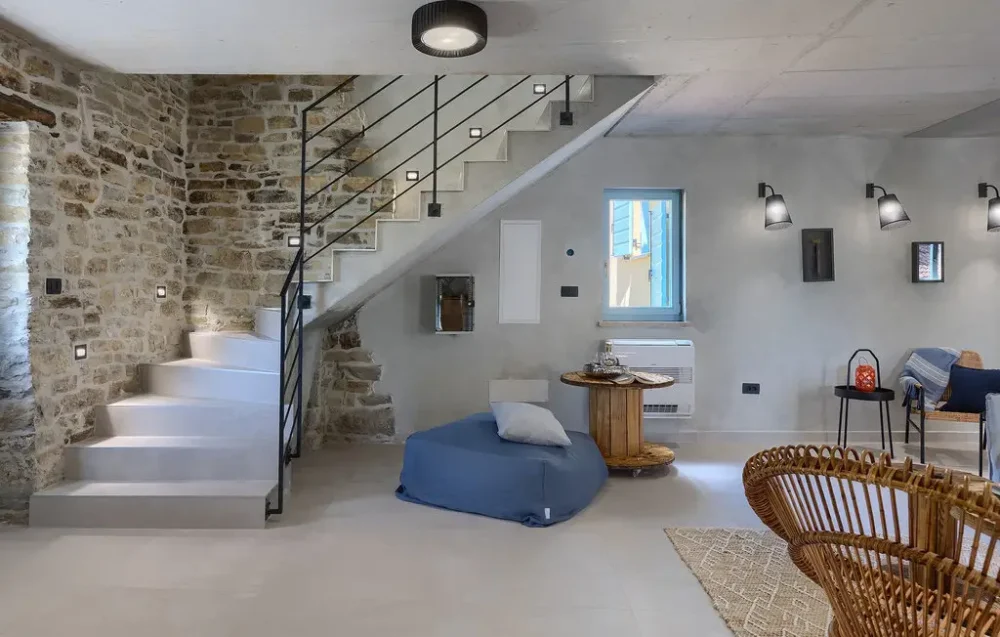Modern rustic living room with stone walls and stairs.