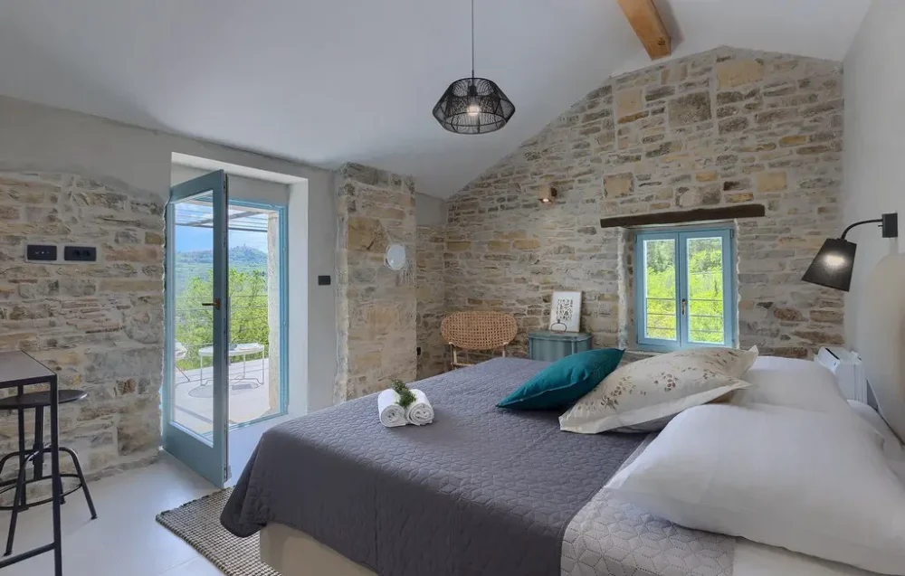 Rustic bedroom with stone walls and open door.