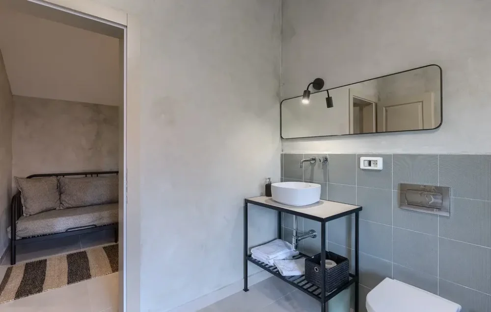 Modern bathroom with sink, mirror, and sofa bed.