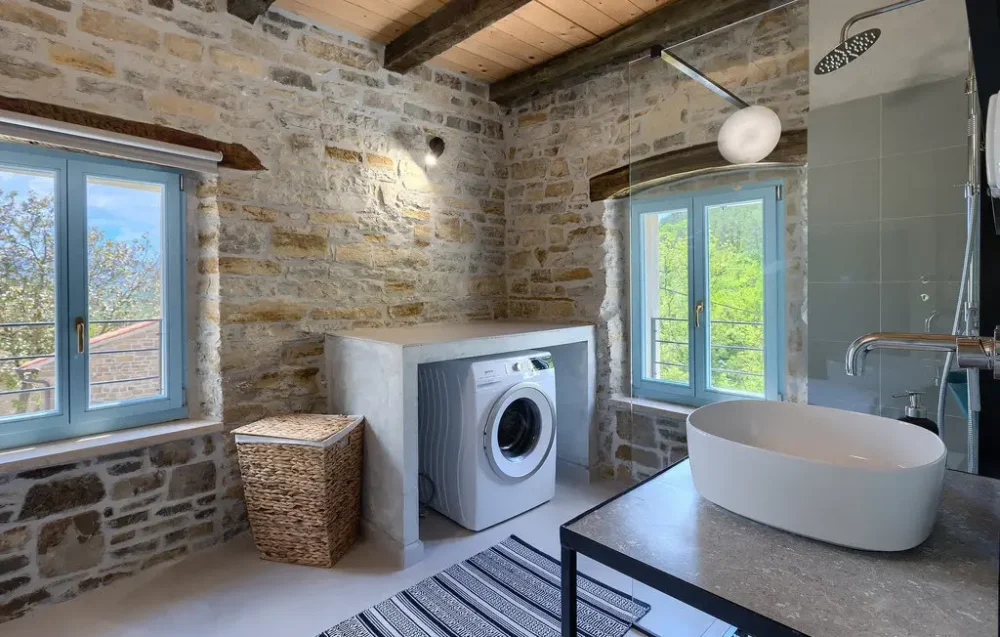 Rustic bathroom with washer and stone walls.