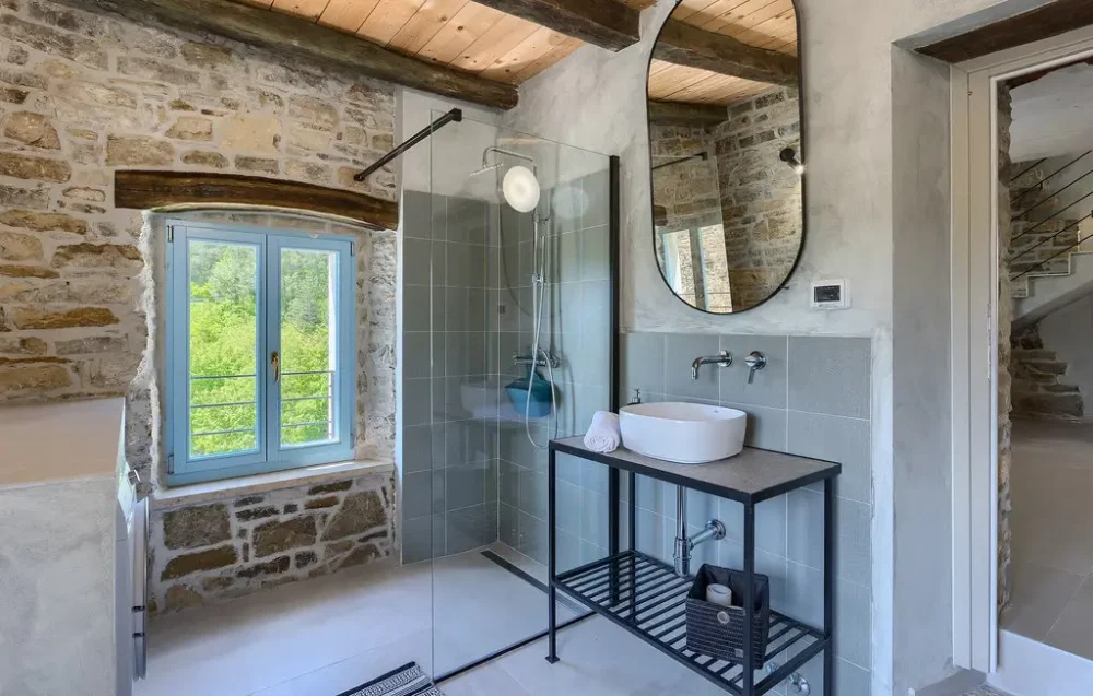 Rustic bathroom with stone walls and modern fixtures.