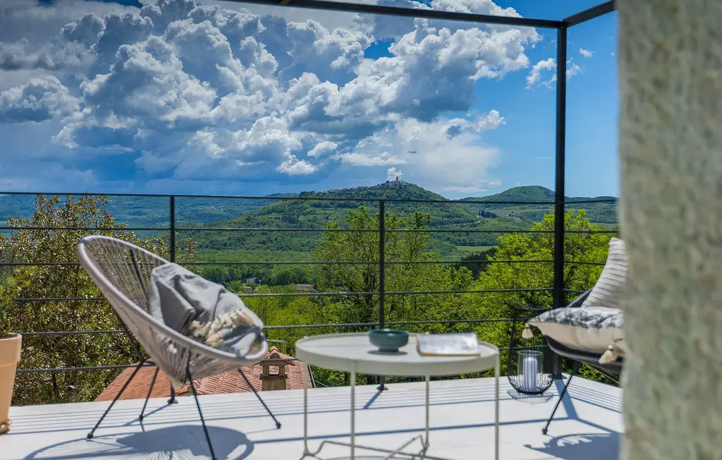Scenic view from balcony with hills and clouds.
