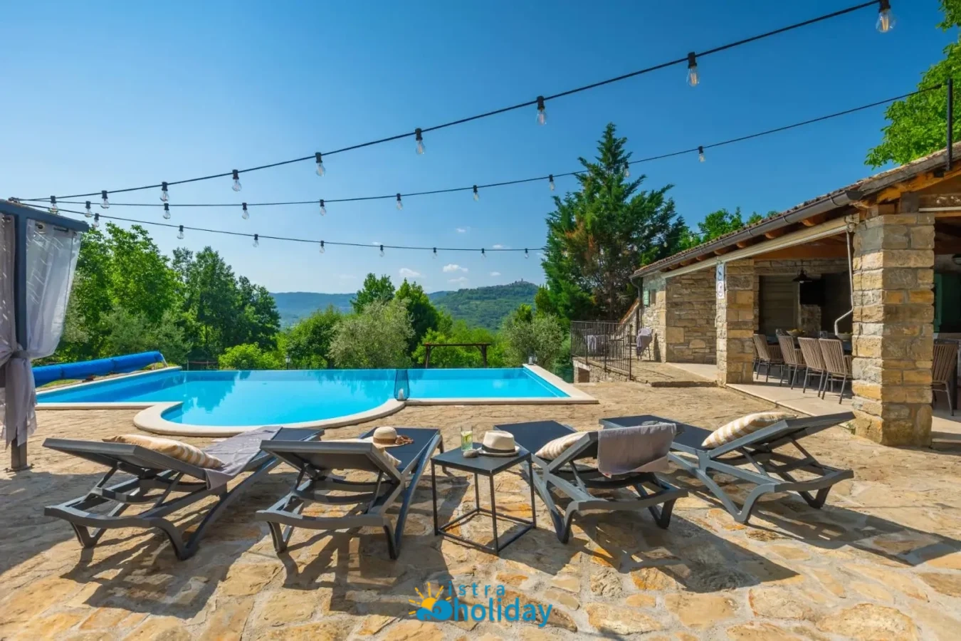 Outdoor pool with loungers and stone terrace.