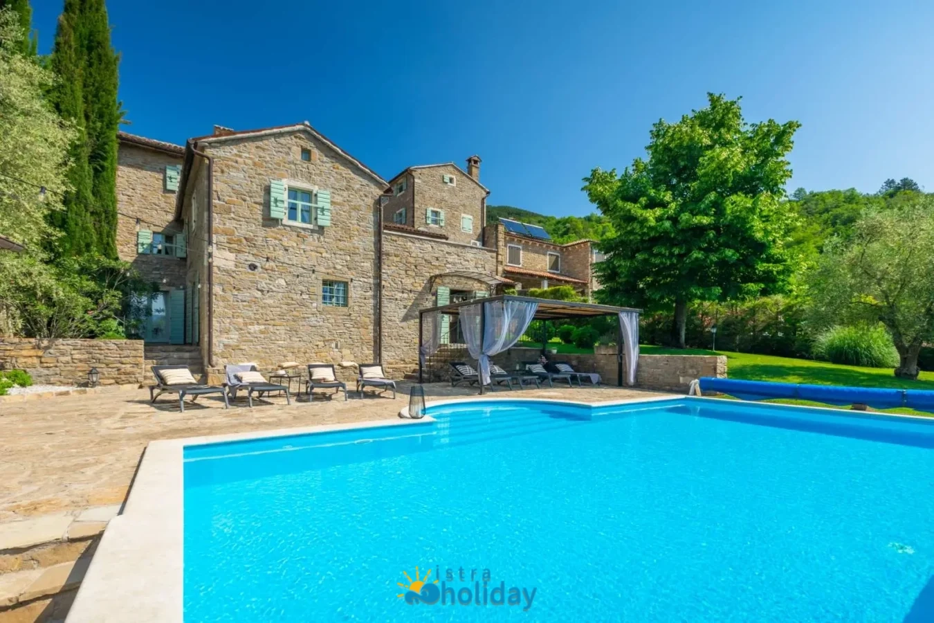Stone villa with pool and lush garden view.