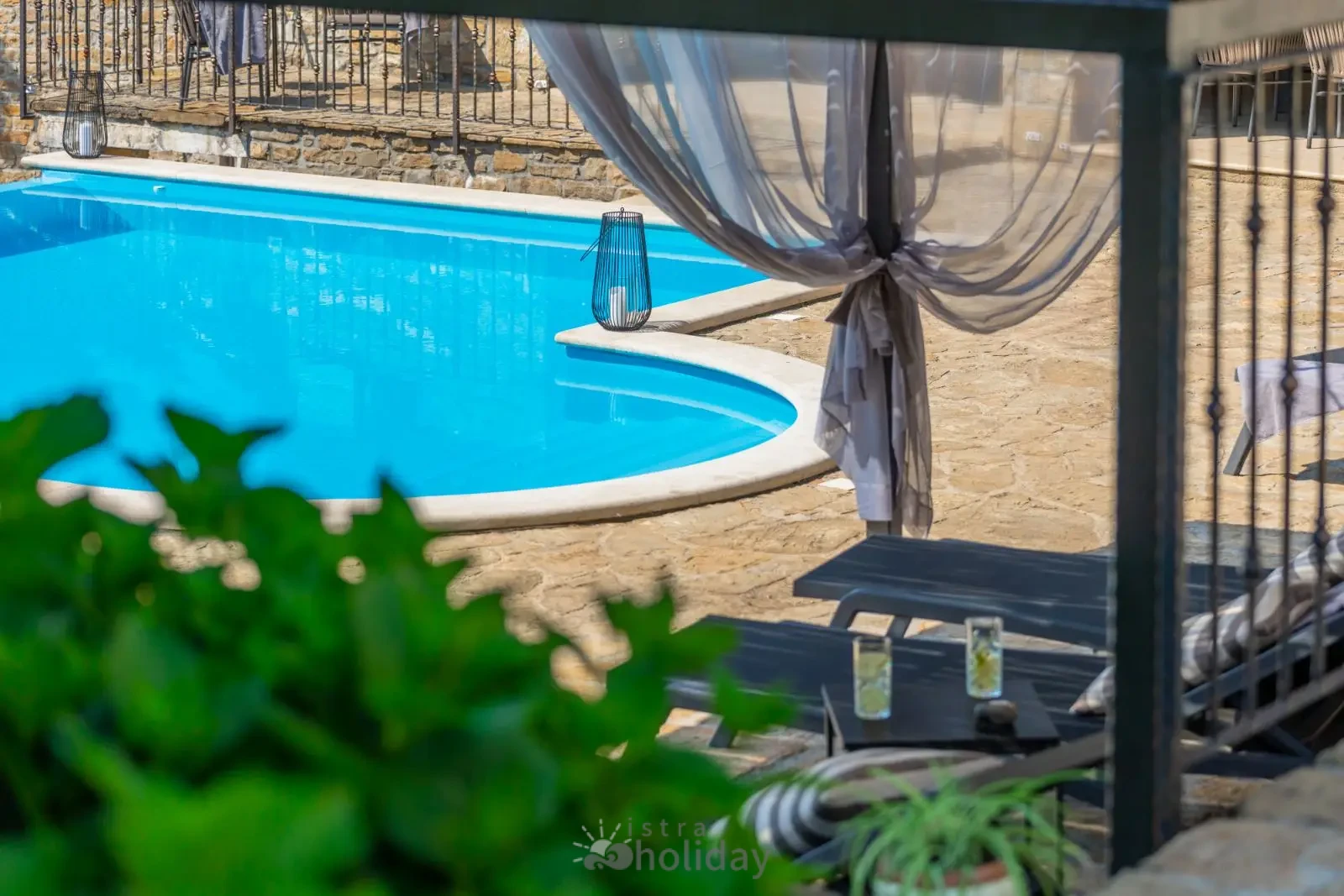 Outdoor pool with stone patio and curtains