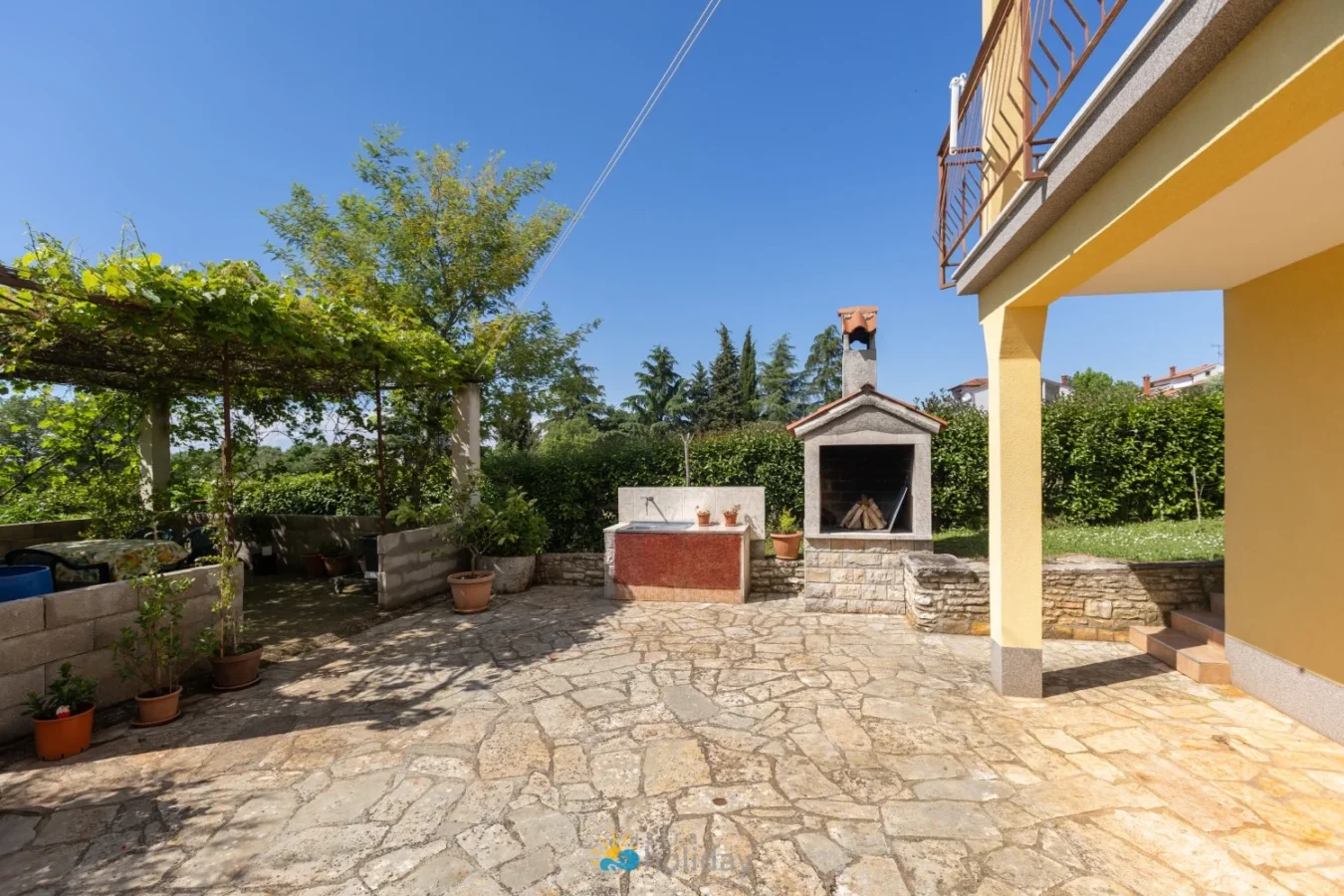Sunny backyard patio with stone grill and pergola