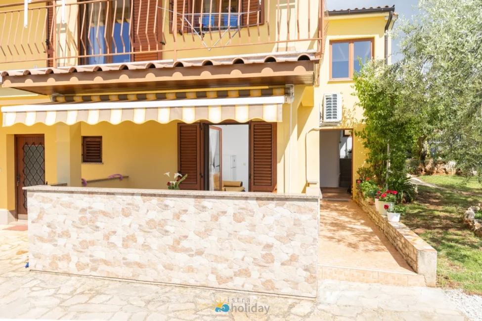Yellow Mediterranean house with patio and awning