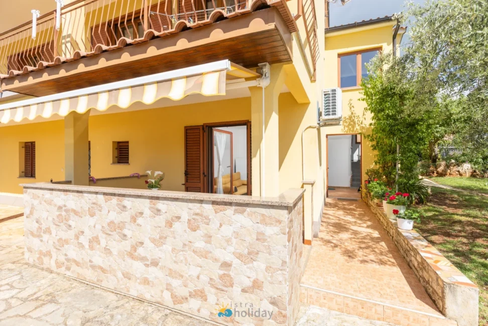 Yellow house with covered patio and striped awning