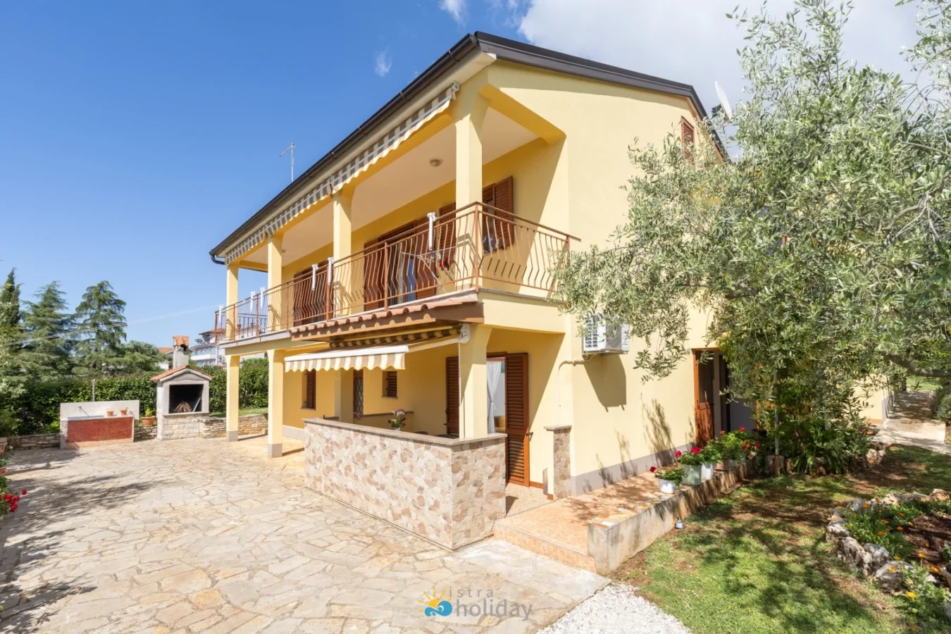 Two-story yellow house with balcony and patio