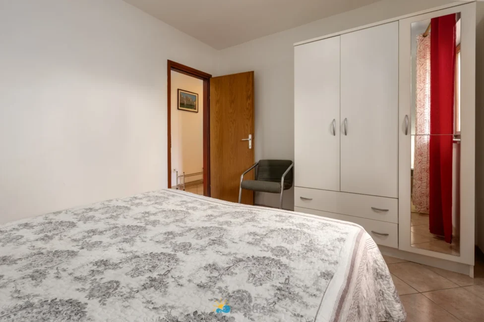 Simple bedroom with wardrobe, chair, and open door