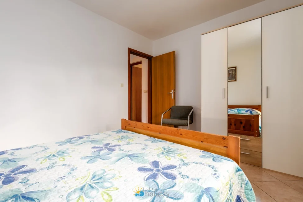 Simple bedroom with wooden bed and mirrored wardrobe