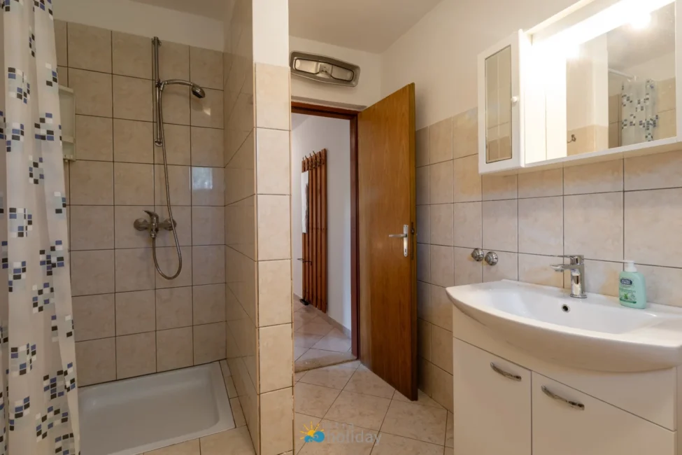 Tiled bathroom with shower, sink, and open door