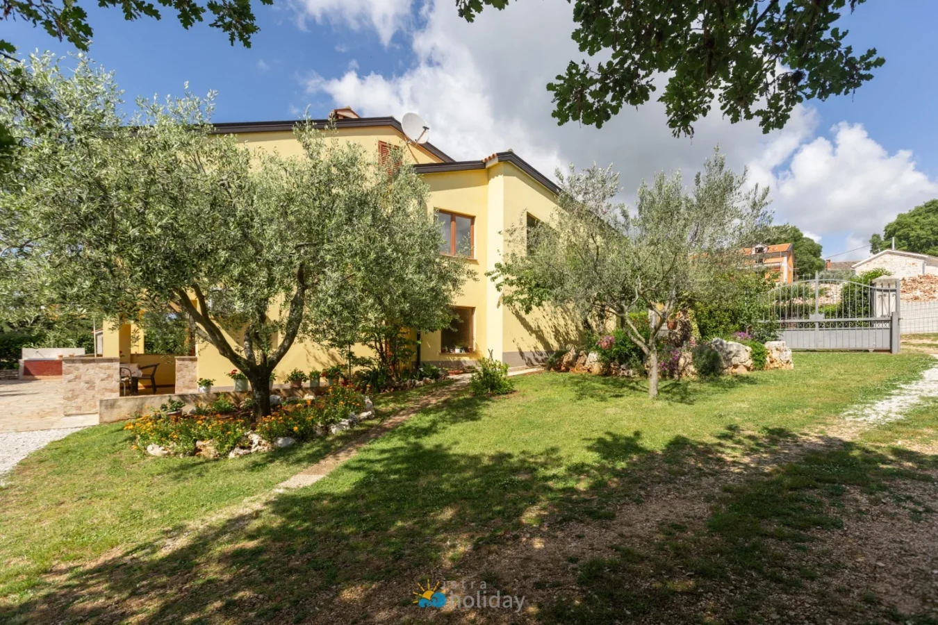 Yellow house with olive trees and garden lawn