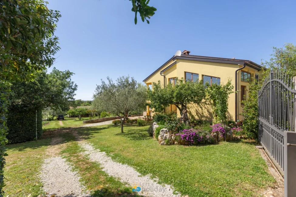 Yellow two-story house with garden and driveway