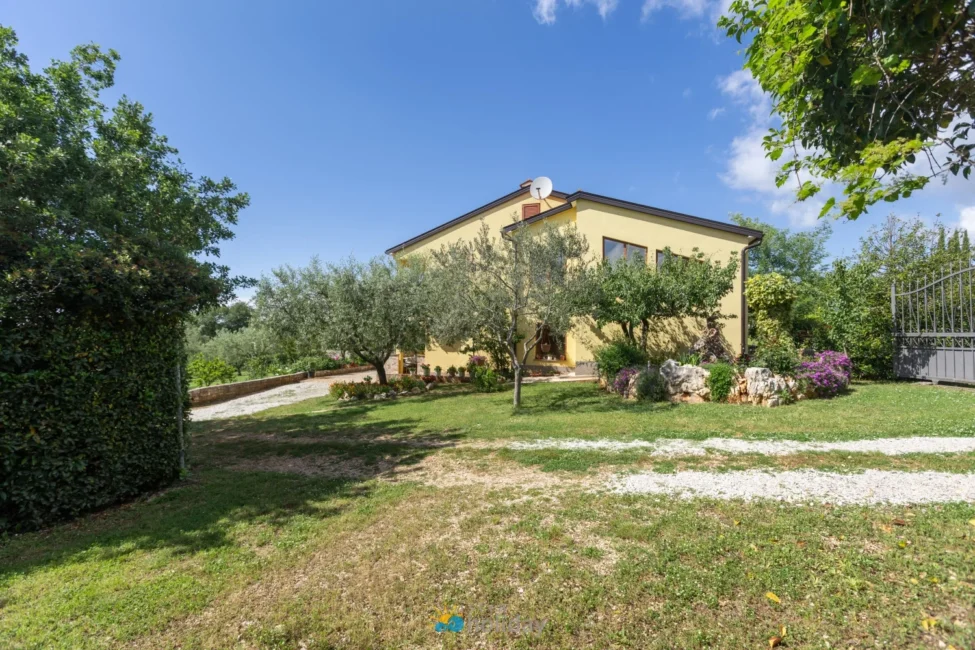 Yellow two-story house with garden and trees