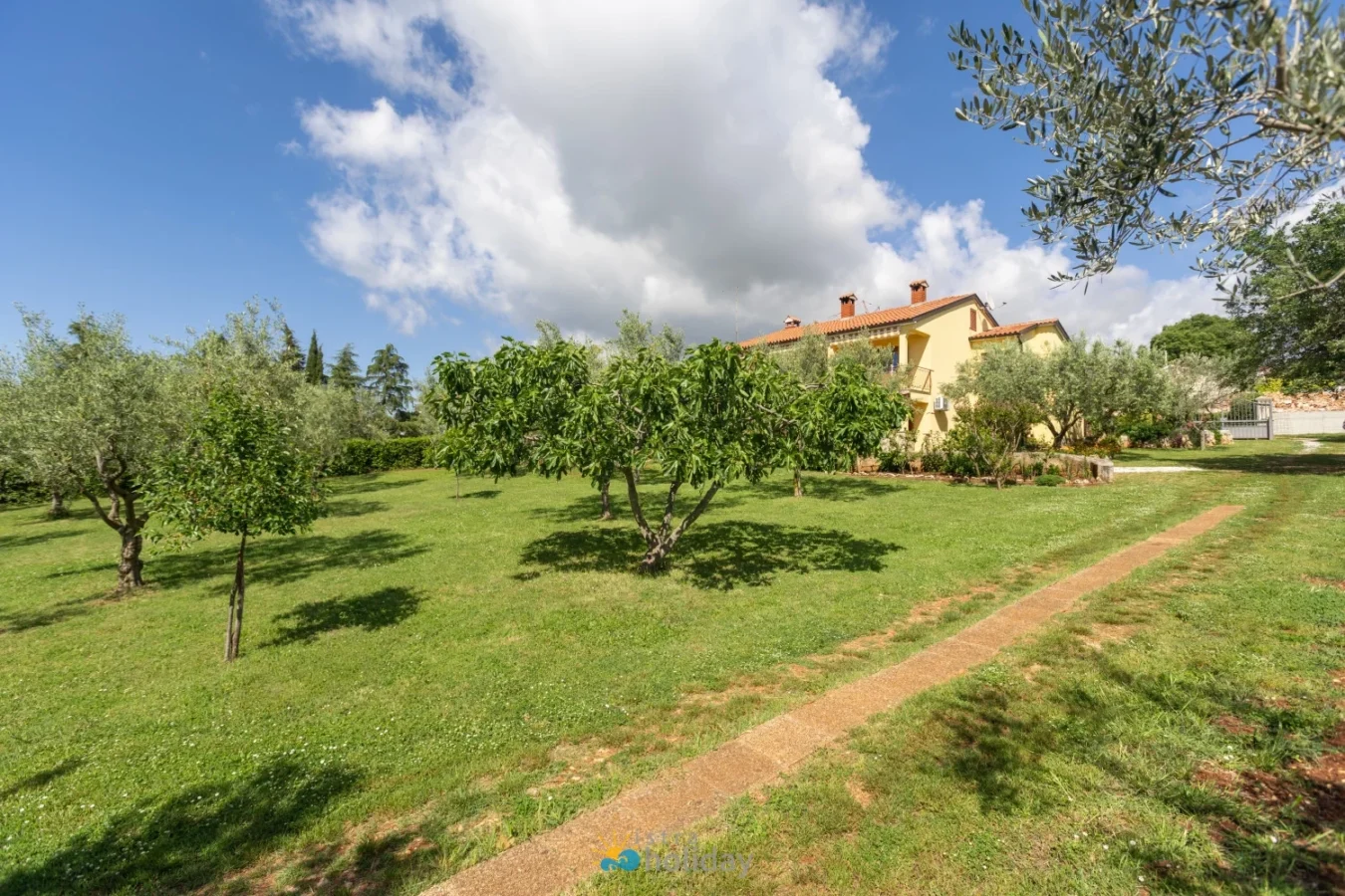 Yellow house with large green lawn and trees