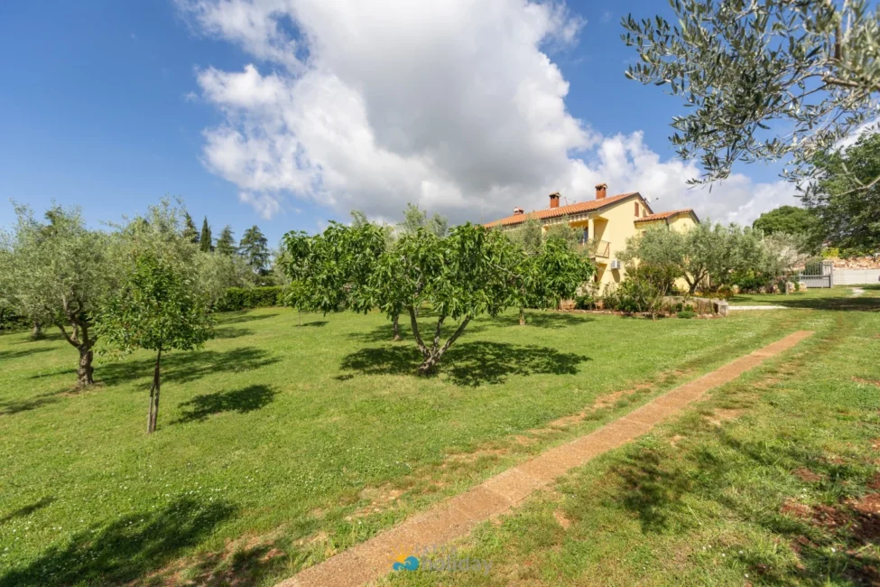 Yellow house with large green lawn and trees