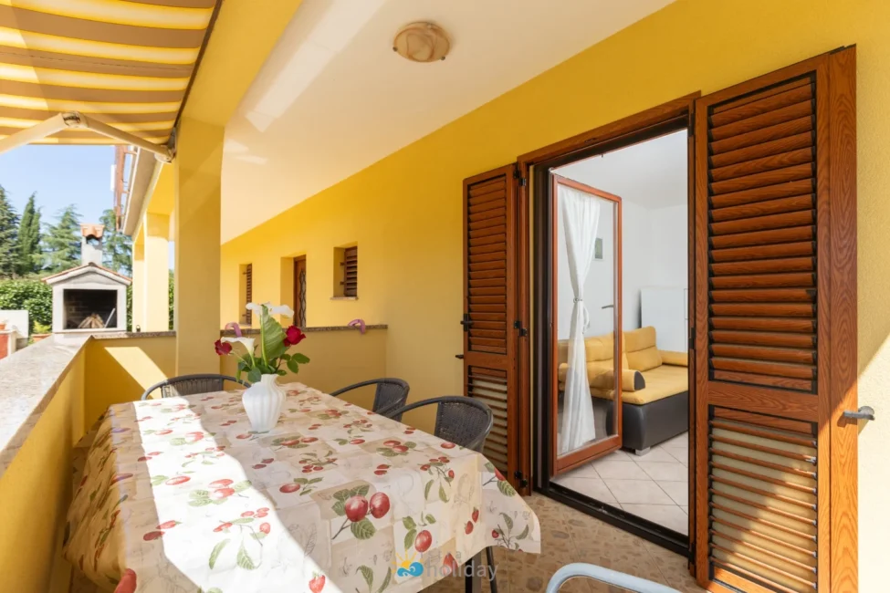 Sunny yellow balcony with table and wooden shutters