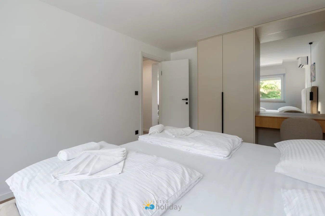Minimalist bedroom with white bedding and mirrored wardrobe
