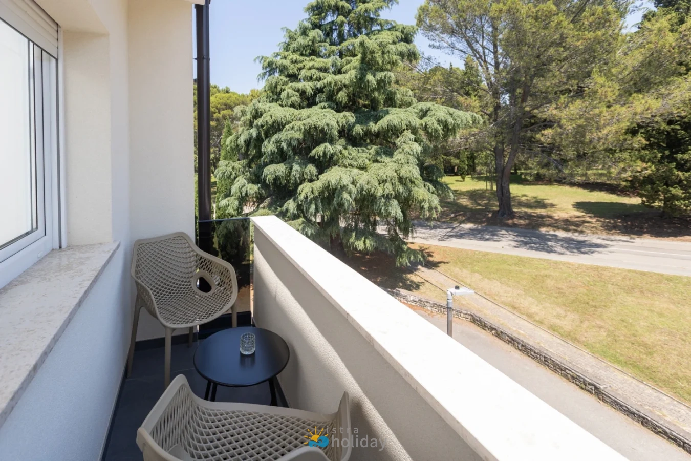 Small balcony with chairs overlooking trees and street
