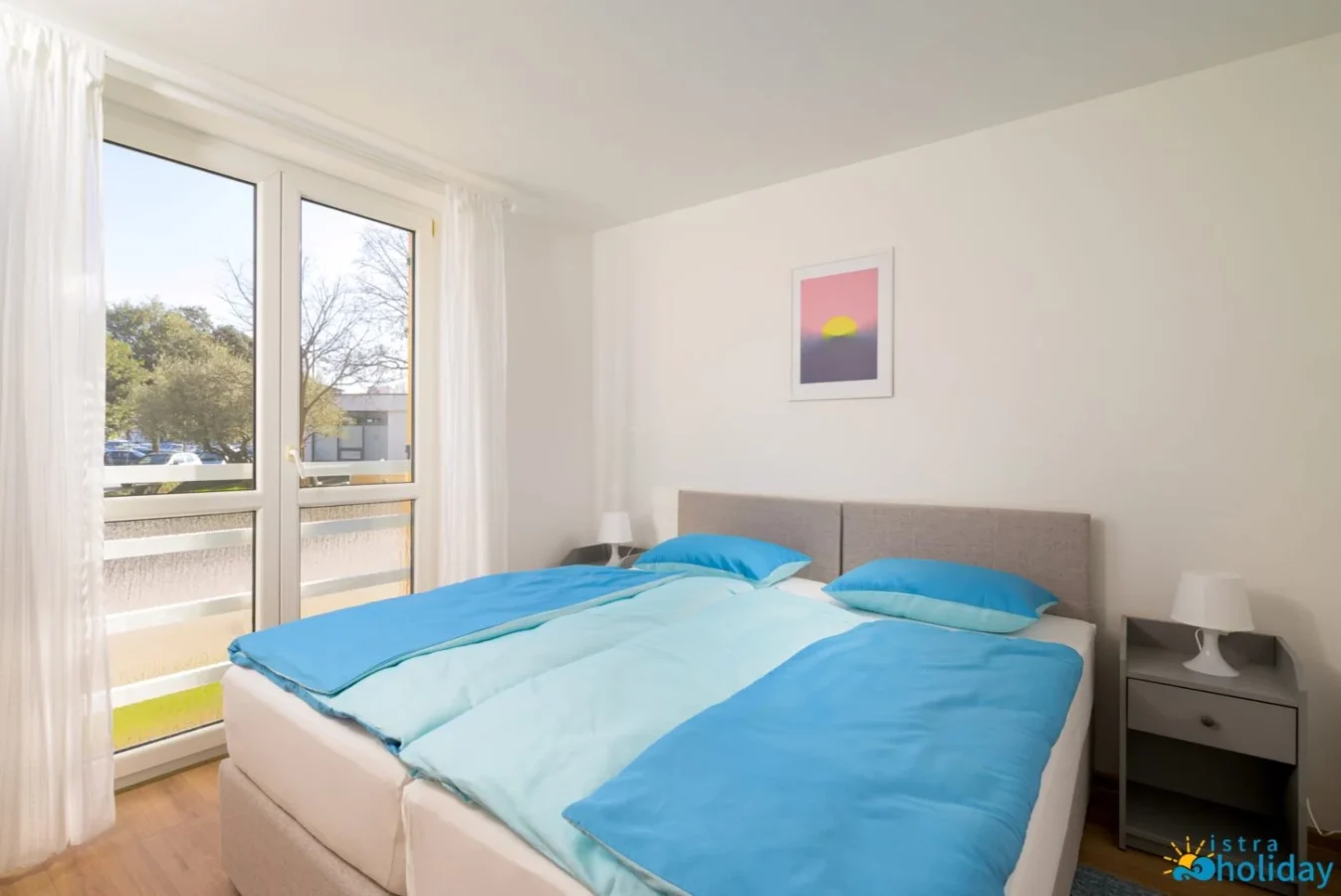 Bright bedroom with window and blue bedding.
