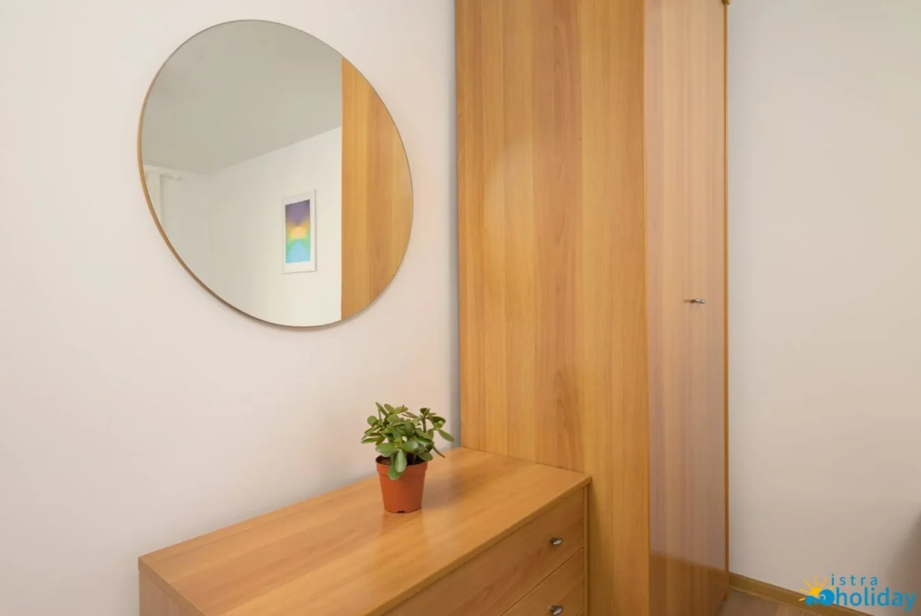 Minimalist wooden wardrobe with round mirror and plant