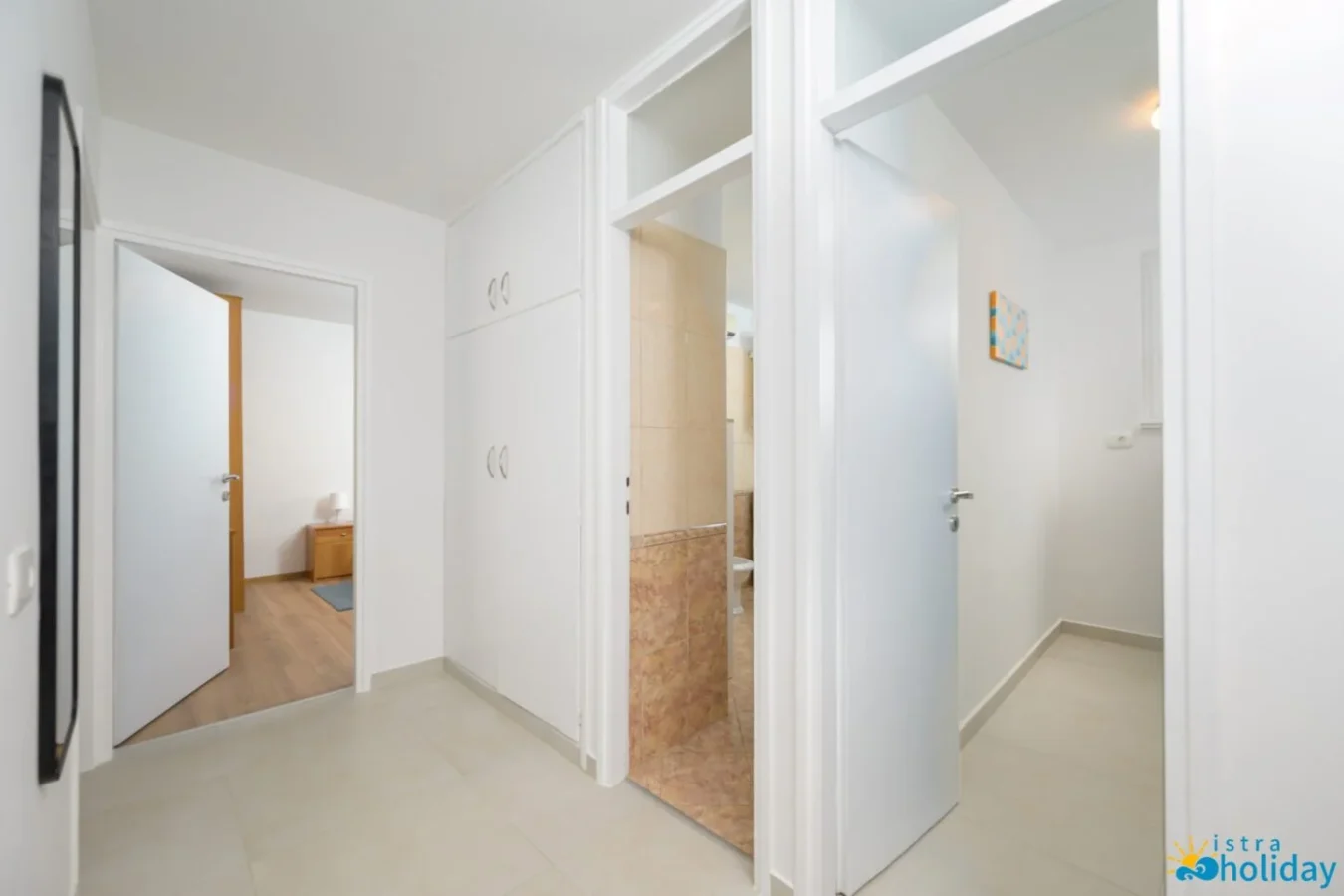 White hallway with doors to rooms and bathroom.
