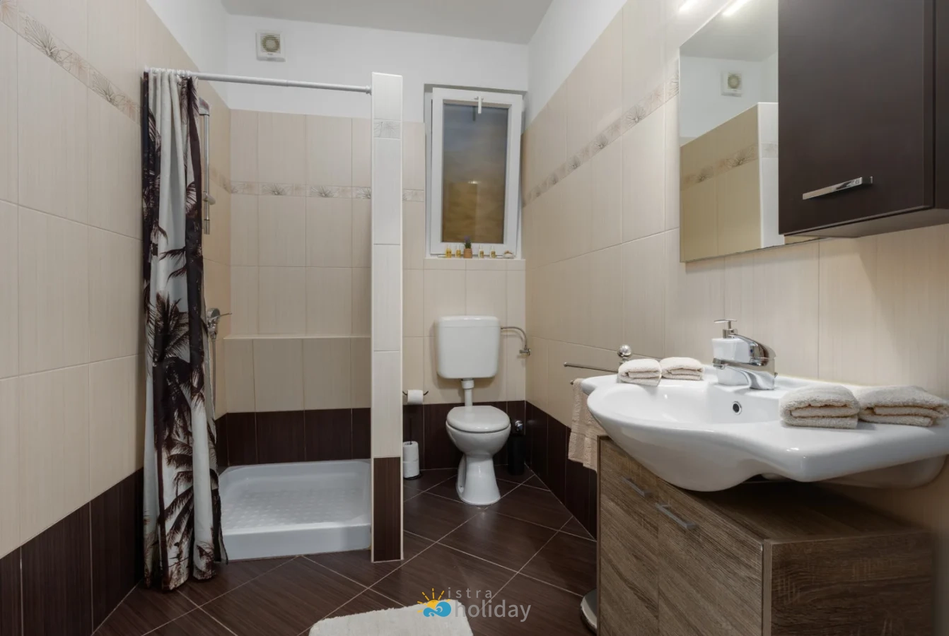 Modern tiled bathroom with shower, toilet, and sink