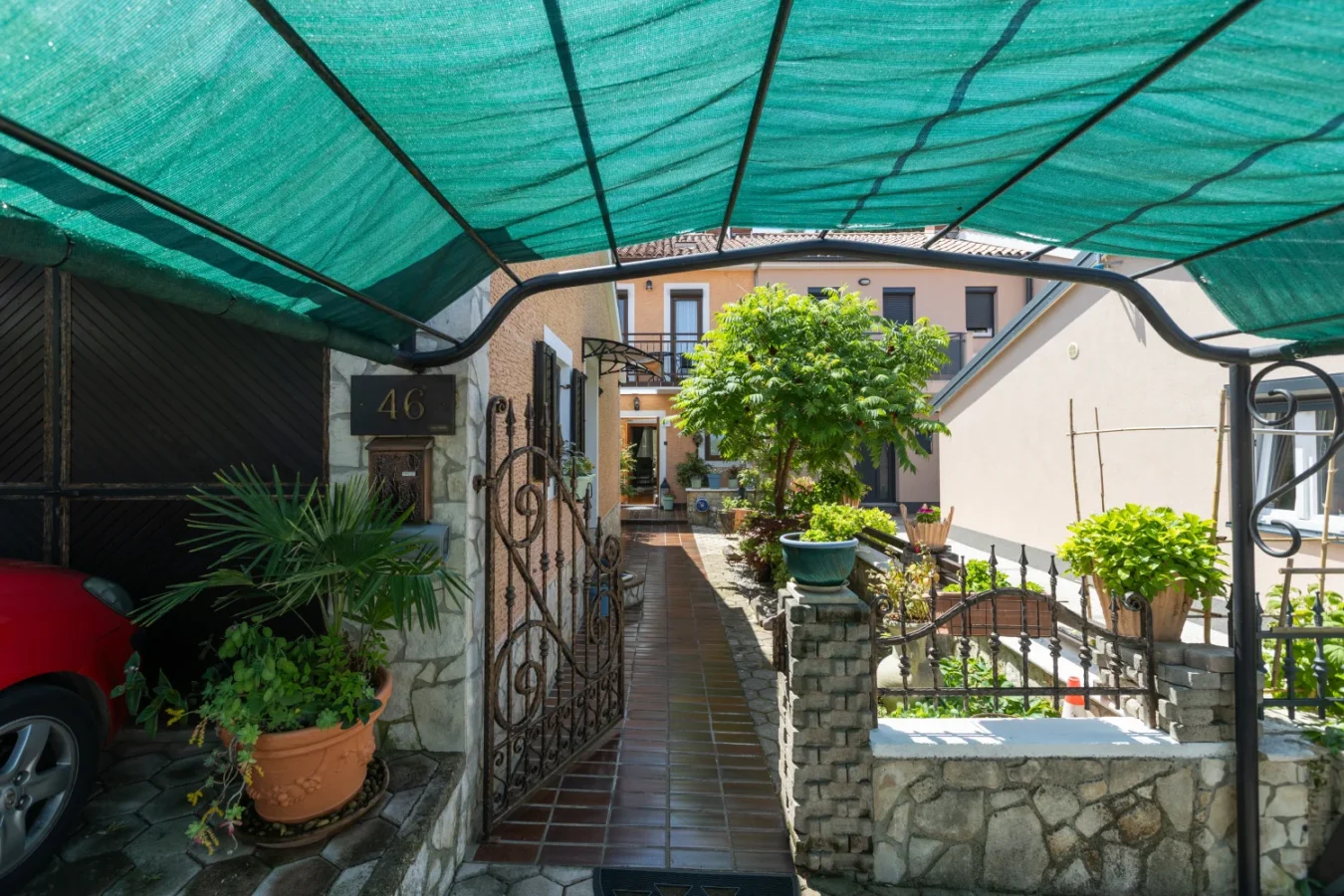 Shaded courtyard entrance with plants and tiled walkway
