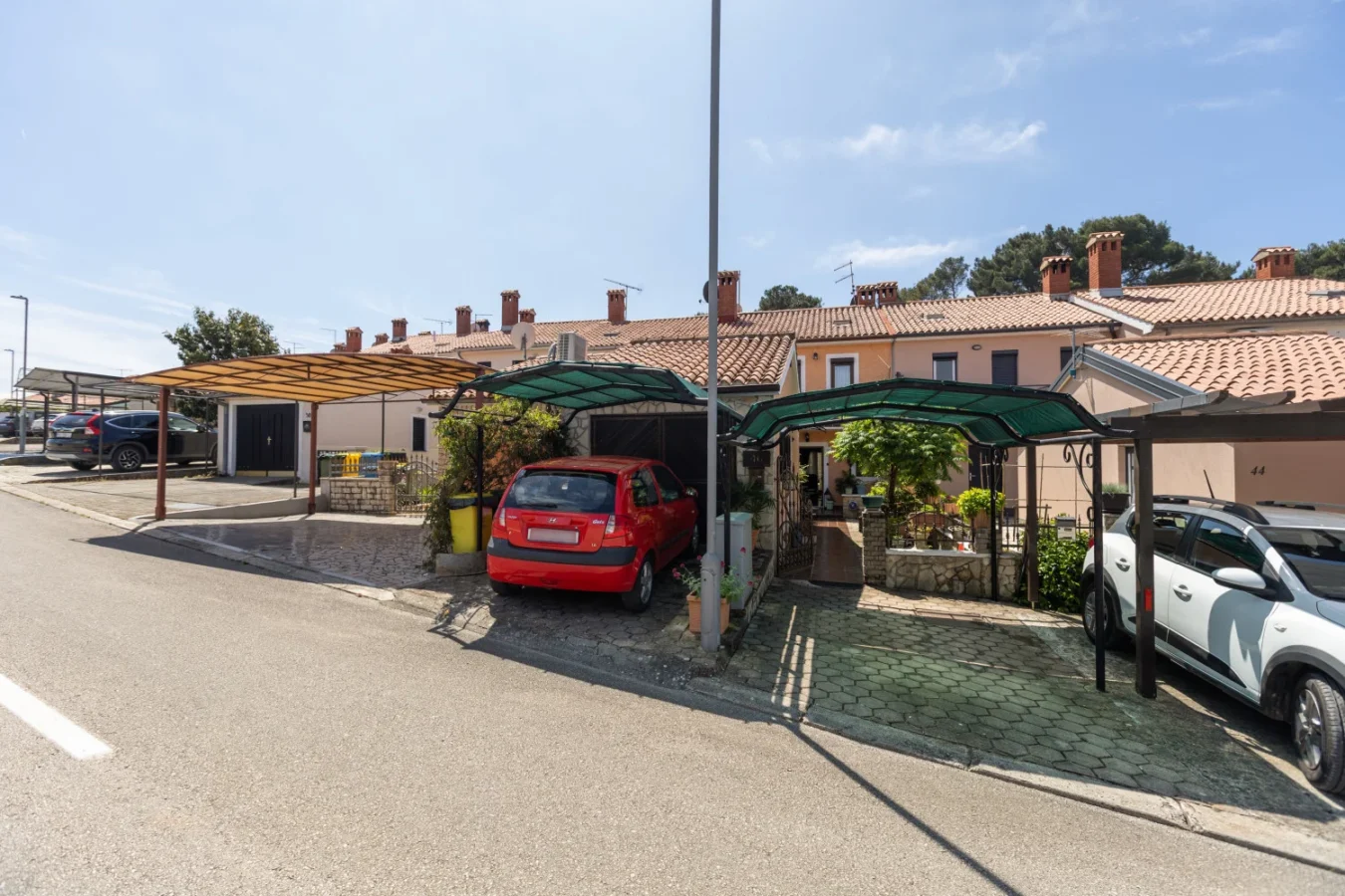 Row of townhouses with carports and parked cars