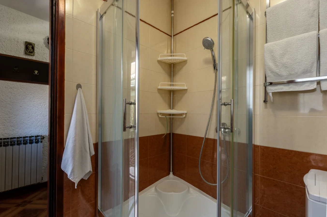 Corner shower with glass doors and tiled walls