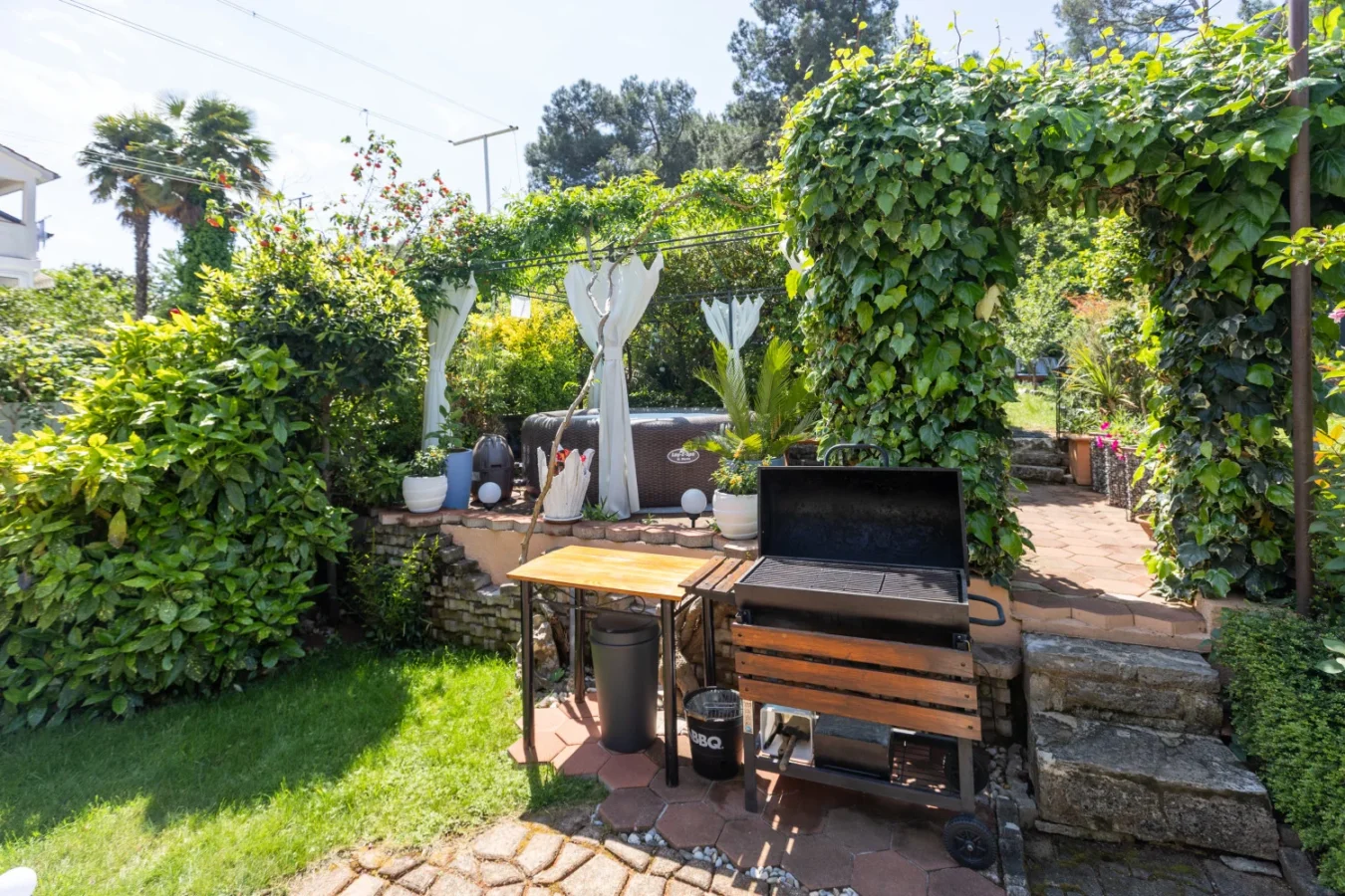 Backyard patio with grill and lush garden pergola