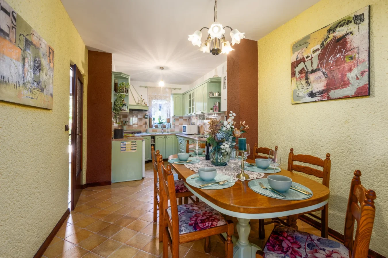 Cozy dining area leading into green kitchen