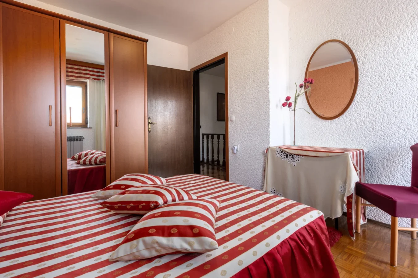 Cozy bedroom with red striped bedding and mirror