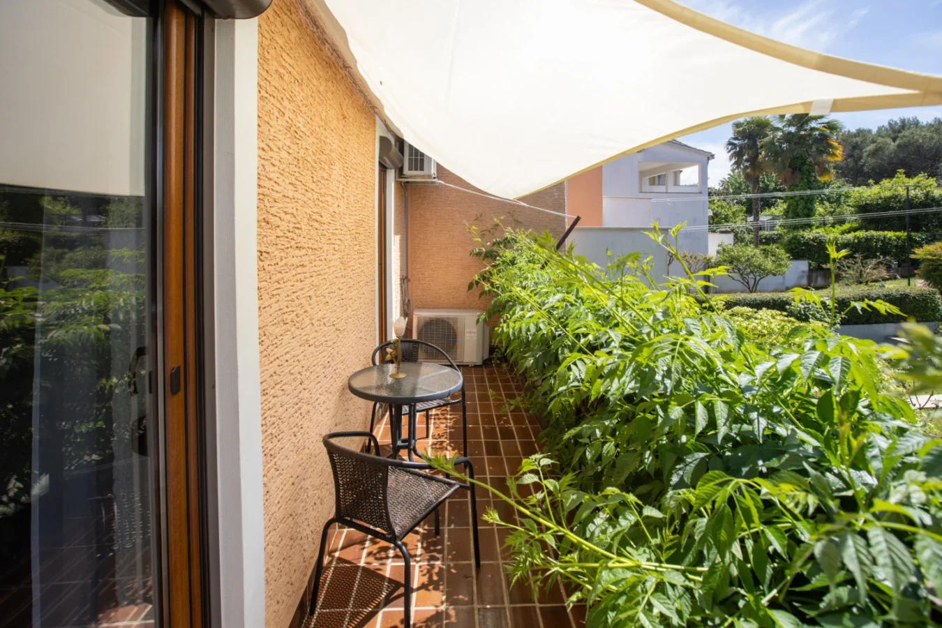 Small balcony with table, chairs, and greenery