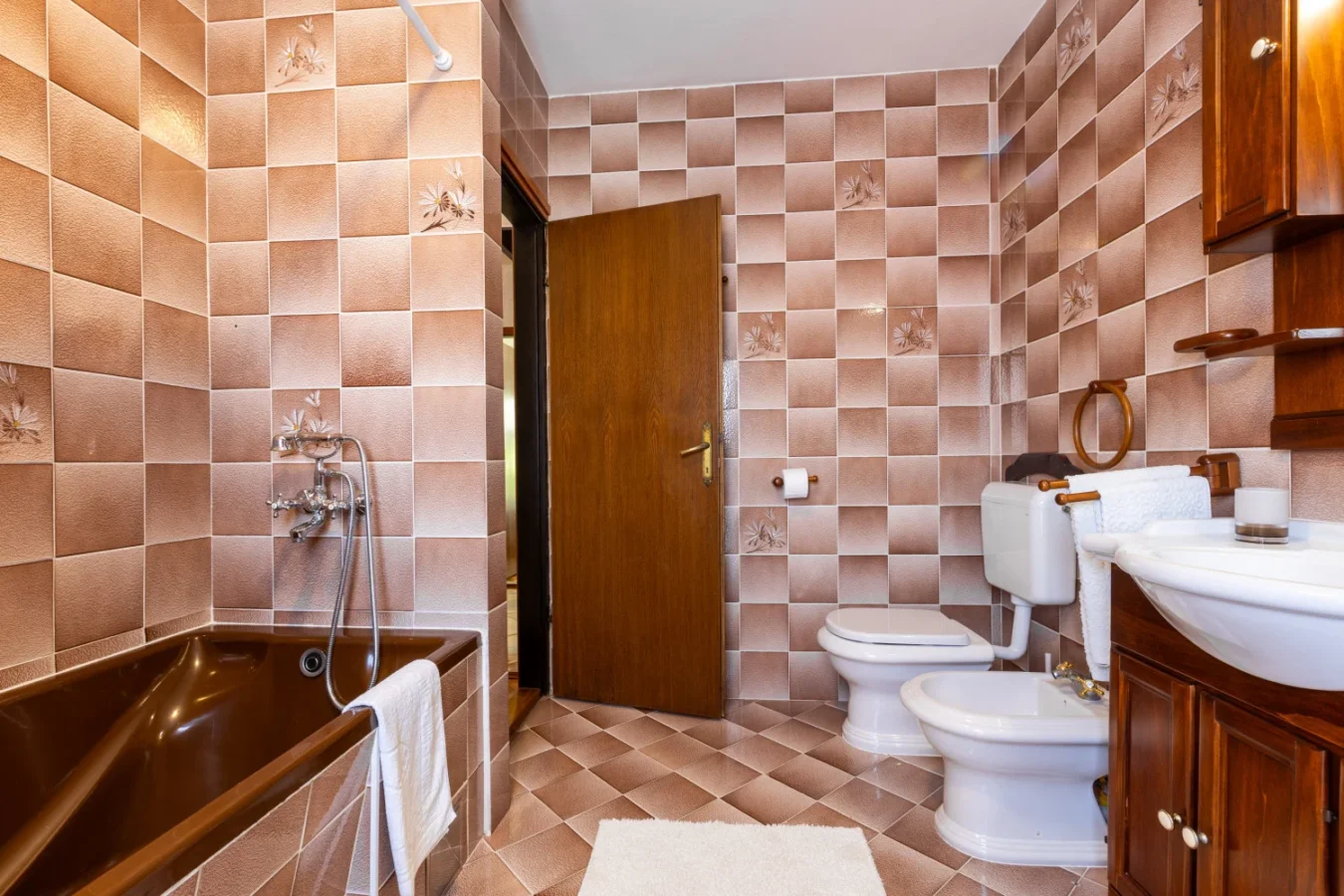 Vintage tiled bathroom with bathtub, toilet, and bidet