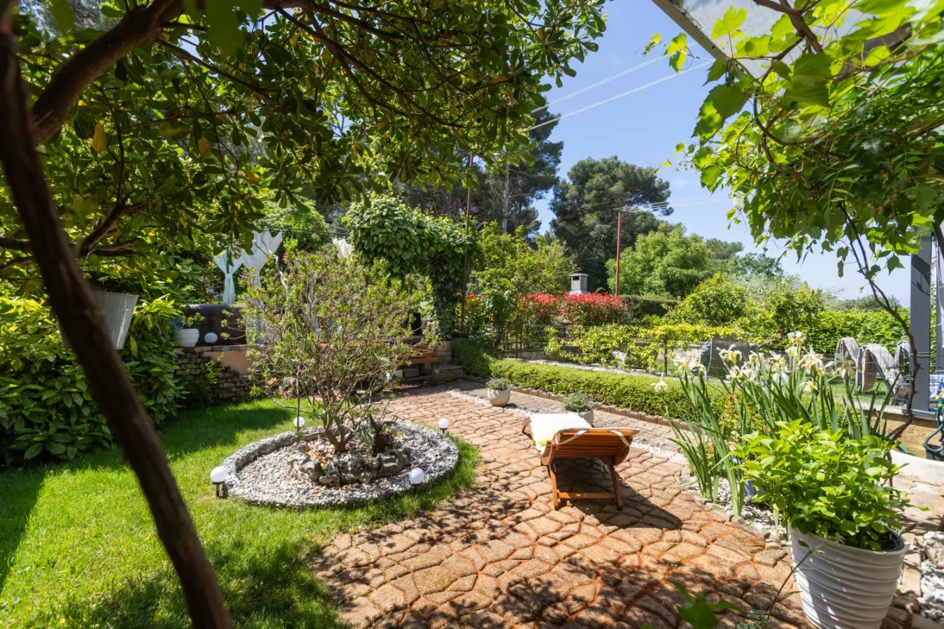 Lush garden patio with stone pathway and lounge chair