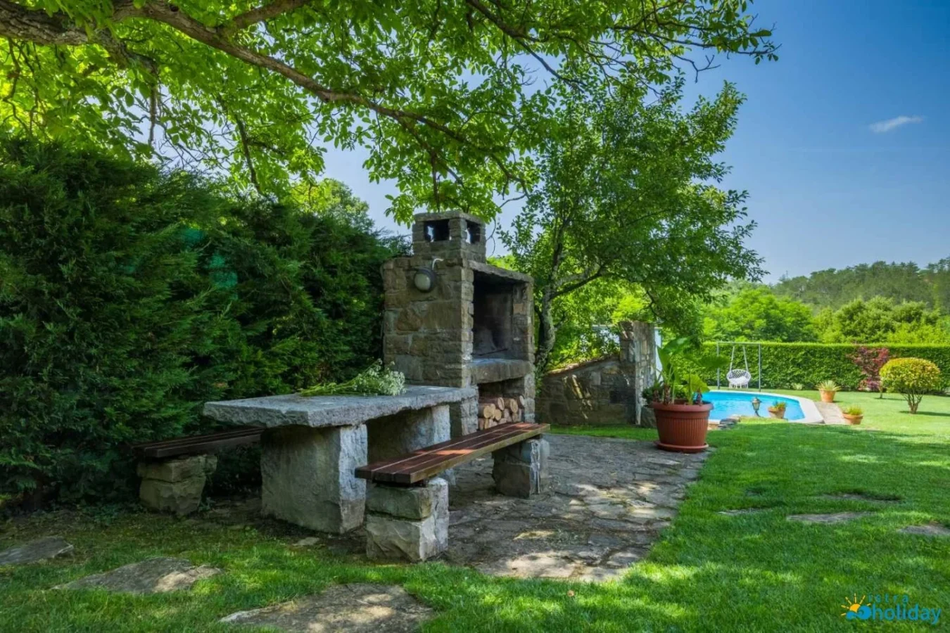 Outdoor stone grill and table in garden setting.