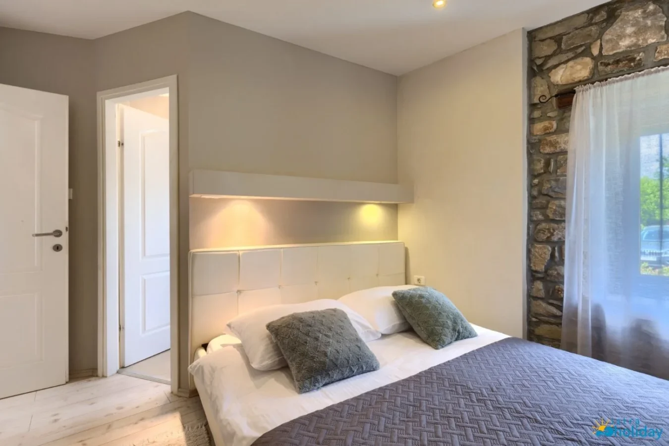 Modern bedroom with stone accent wall and cozy lighting.