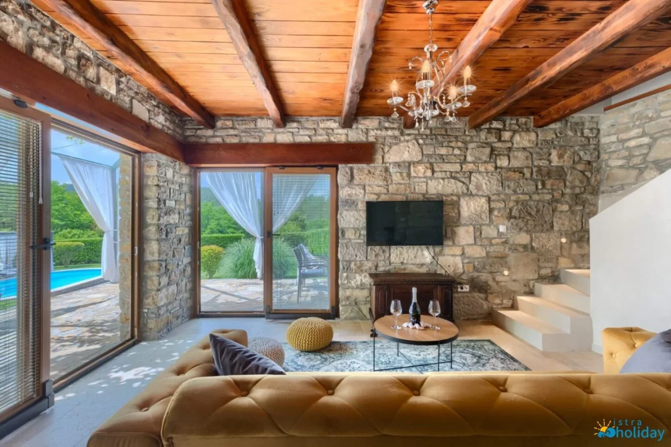 Rustic living room with stone walls and pool view.