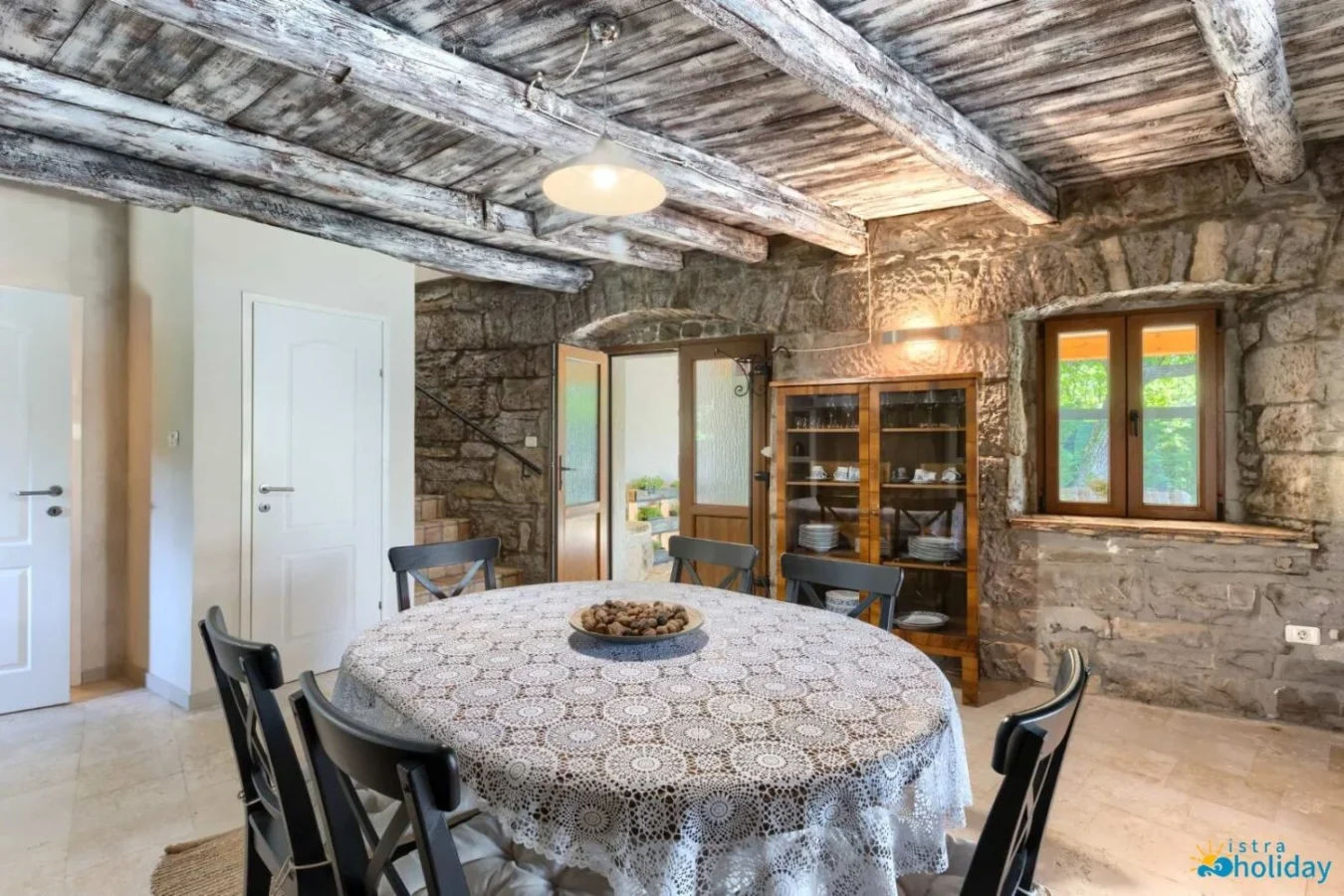 Rustic dining room with stone walls and wooden beams.
